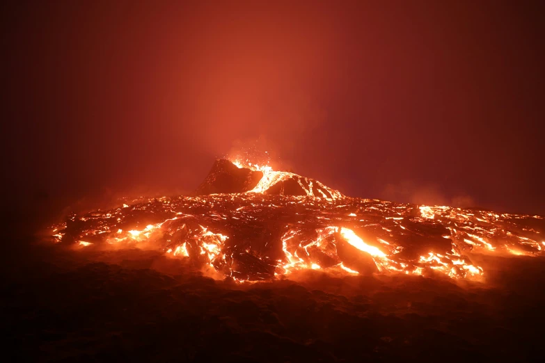 a volcano with lava flowing off it's sides and lots of vegetation burning