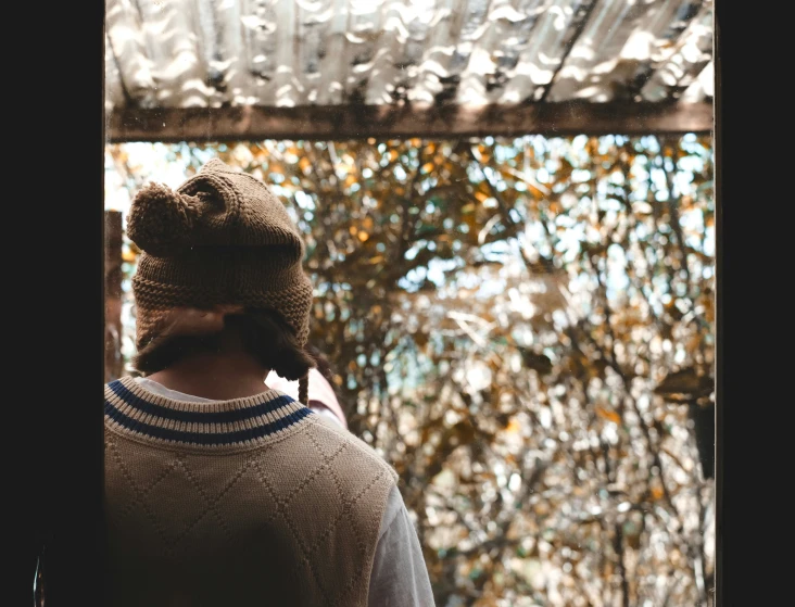 man wearing a knitted hat looking out the window