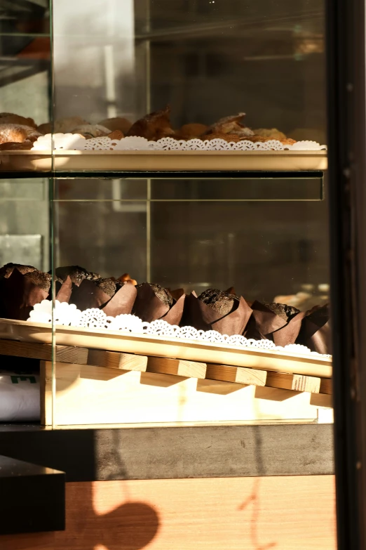 a wooden counter topped with trays of brown and white cakes