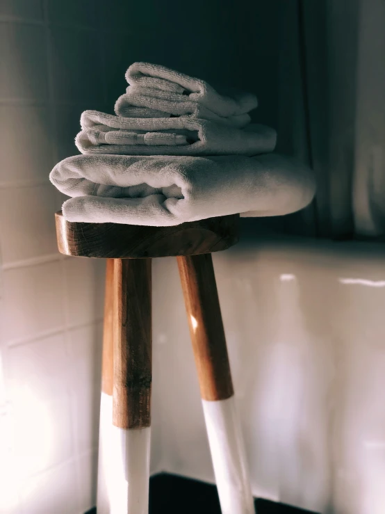 a stack of folded towels sitting on a stool