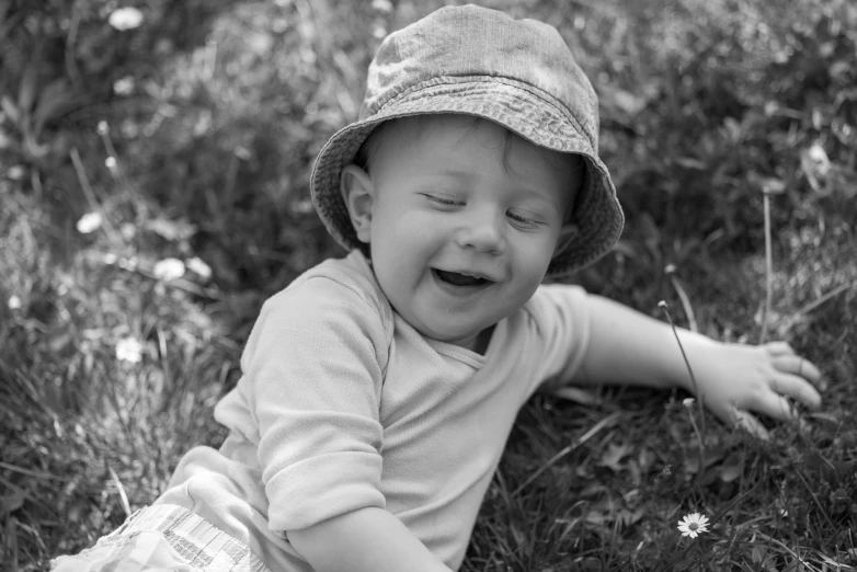 a little boy sitting on the grass with his eyes closed