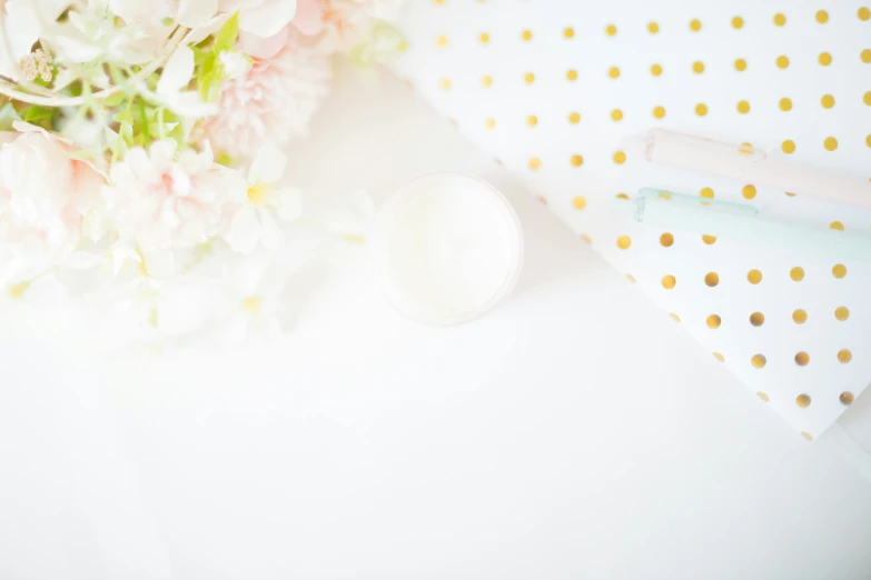 a vase of flowers on a table with an eye mask and wrapping paper next to it