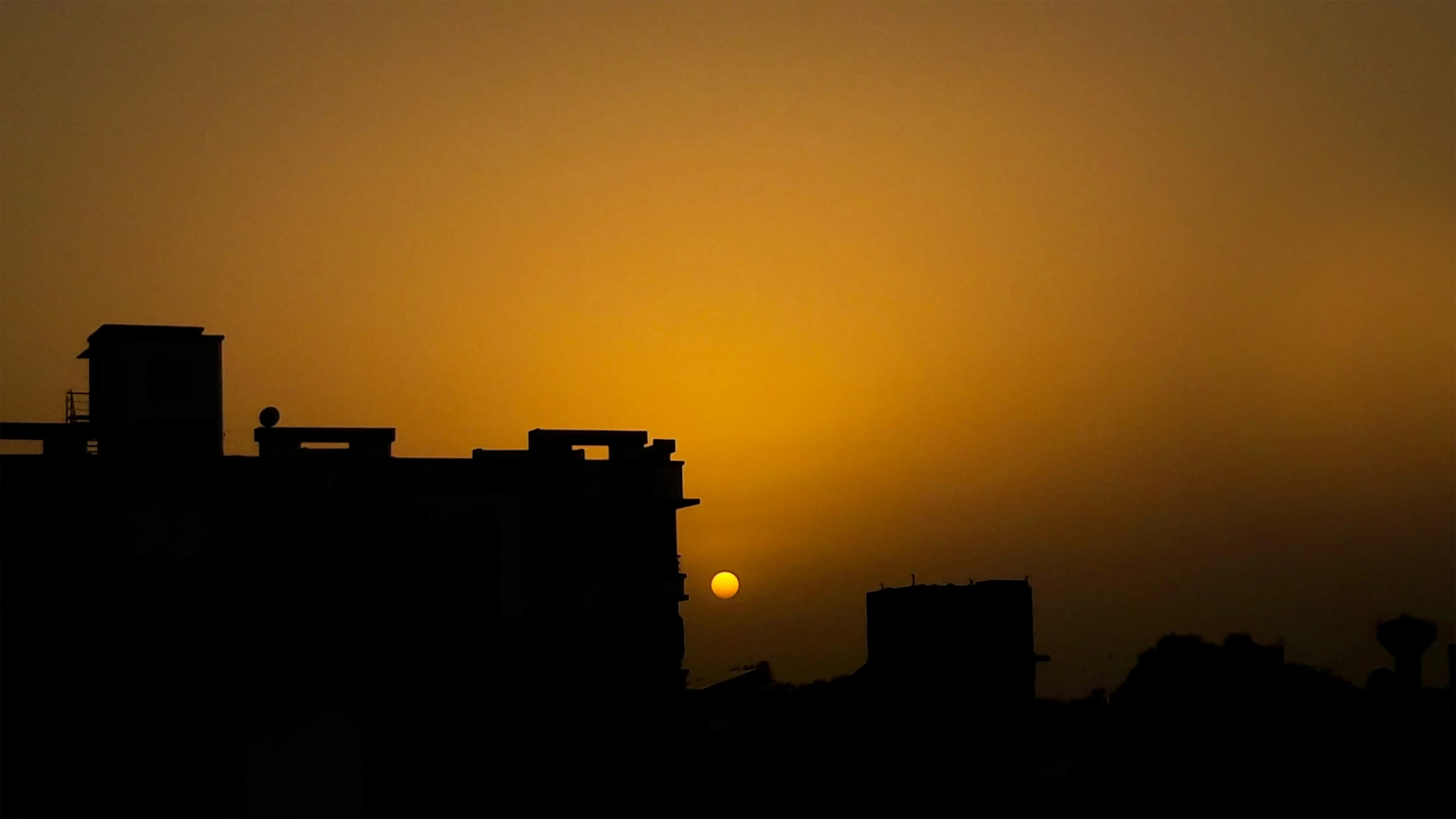 a sun behind a large building and a tall tower