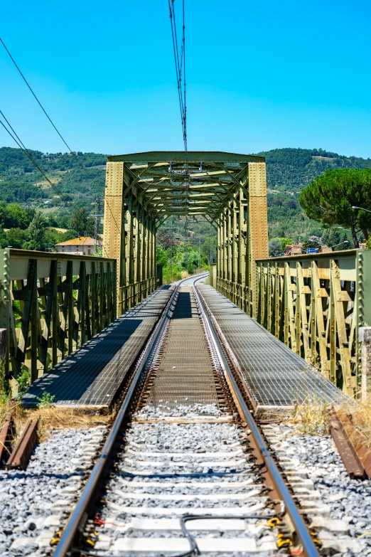 a bridge over a train track running across a hill