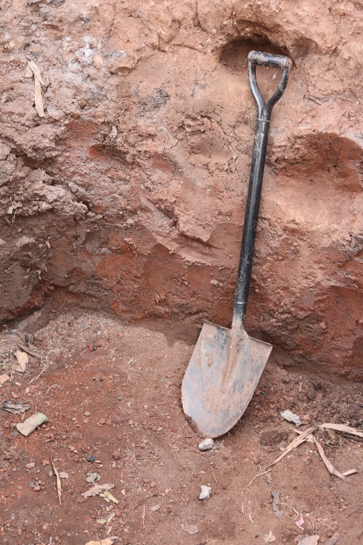 a shovel is left on the ground next to a rock