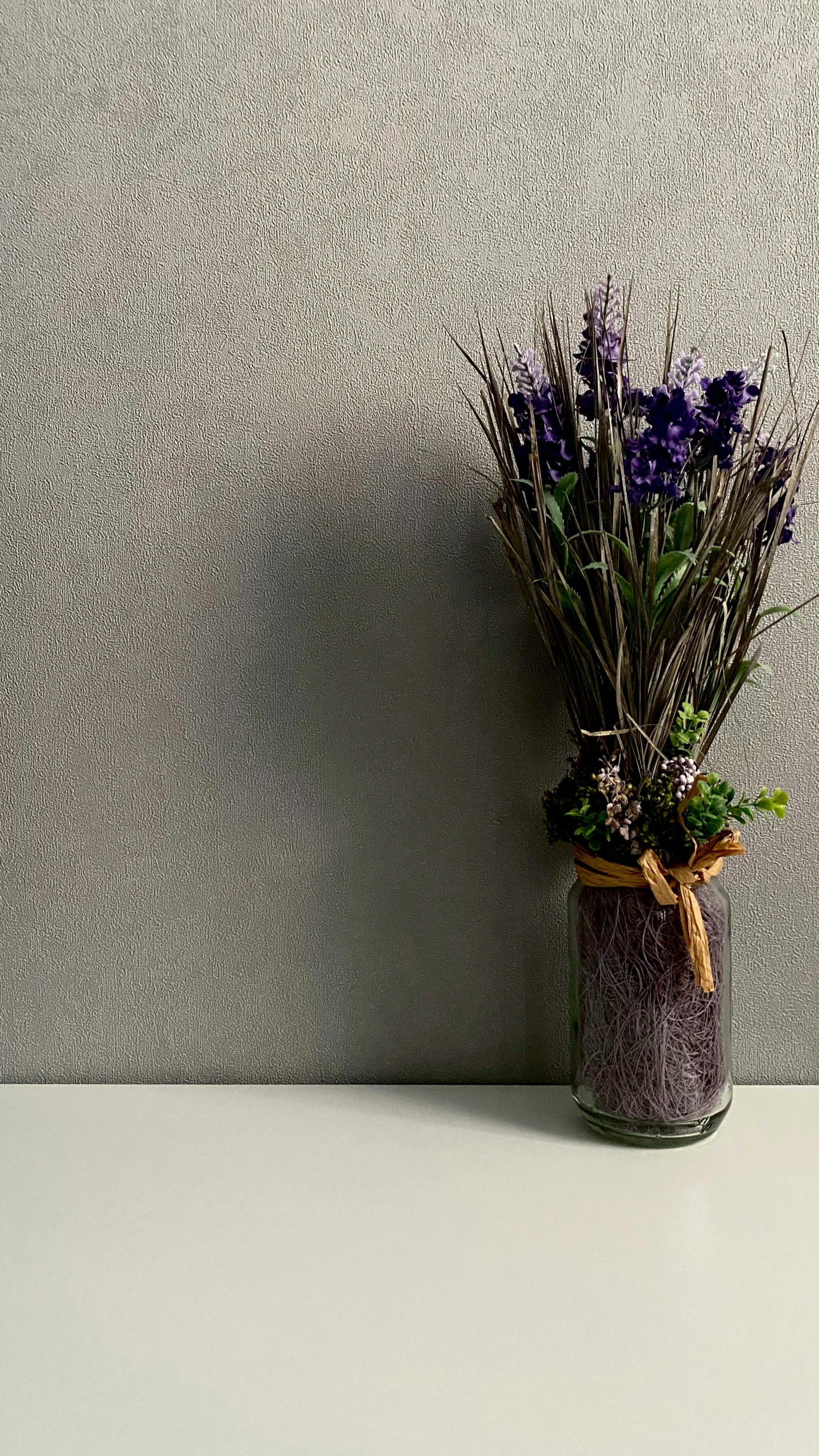 some purple flowers in a clear jar on a table