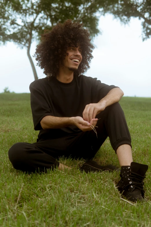 a man with an afro sitting in a field