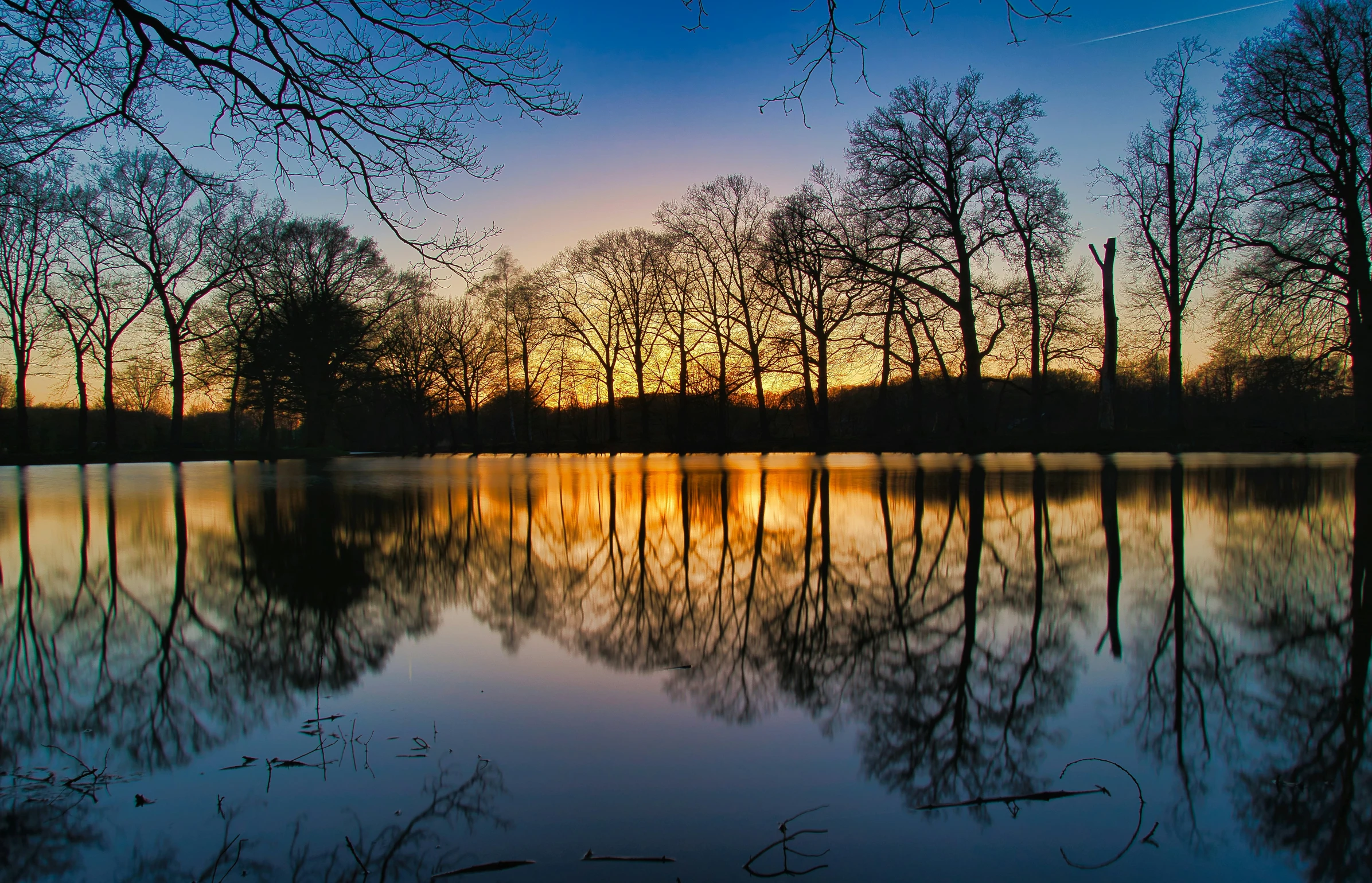 the sky reflected in a pond as it sits at sunset