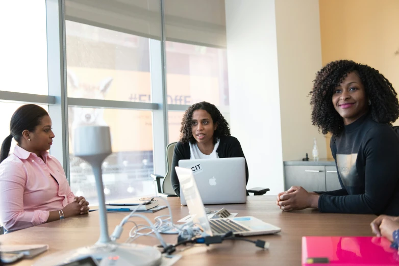 four women sitting at a table with their laptops