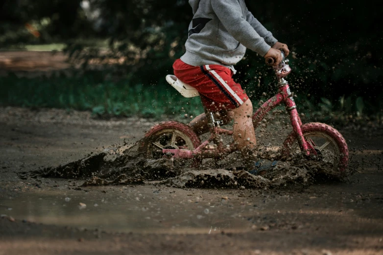 a boy on a little bike is splashing through some water