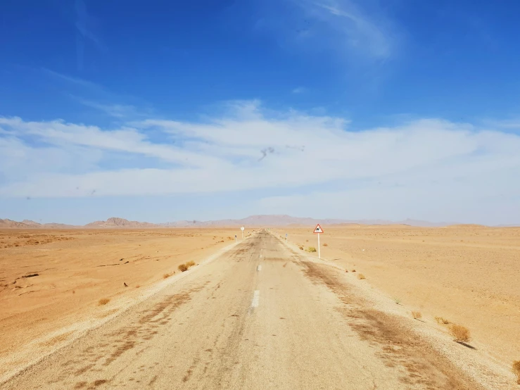 a lone street sign on the middle of an empty desert road