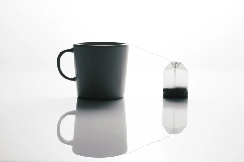 a black cup sits beside a half - empty rectangular mug