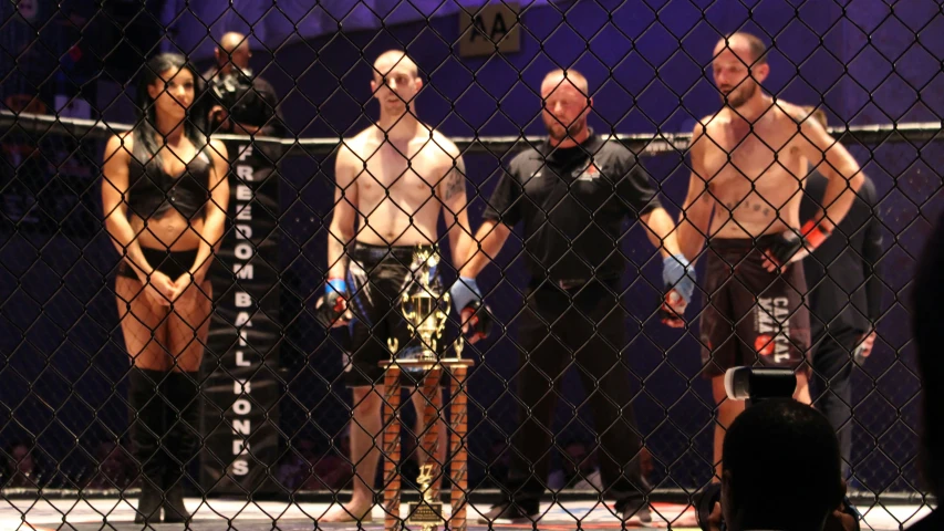 a group of wrestling people standing in front of a cage