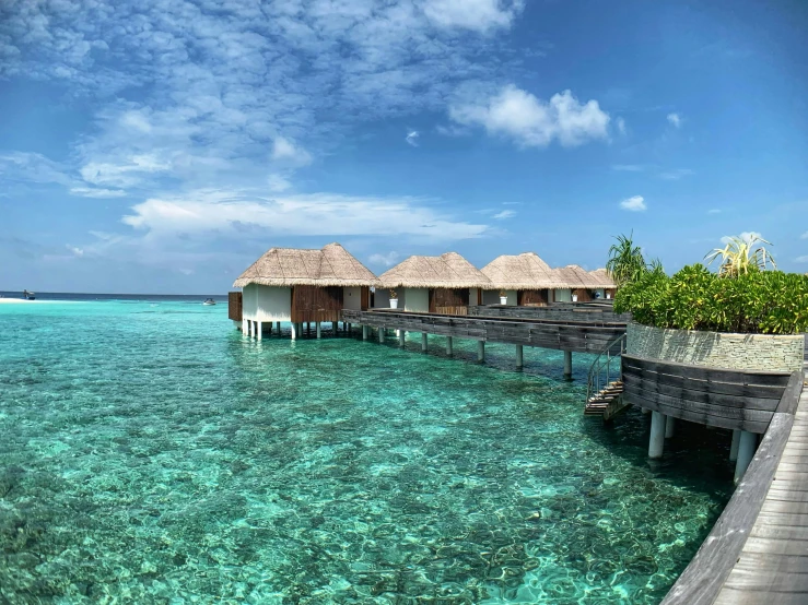 several over water houses at the edge of a large body of clear blue water