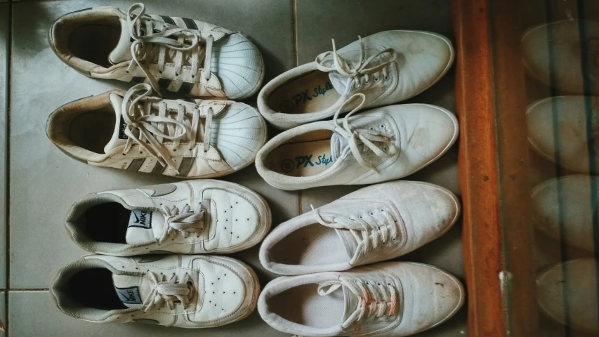 five white tennis shoes arranged on a tile floor