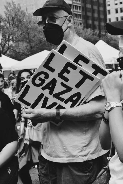 two people holding protest signs while wearing face masks