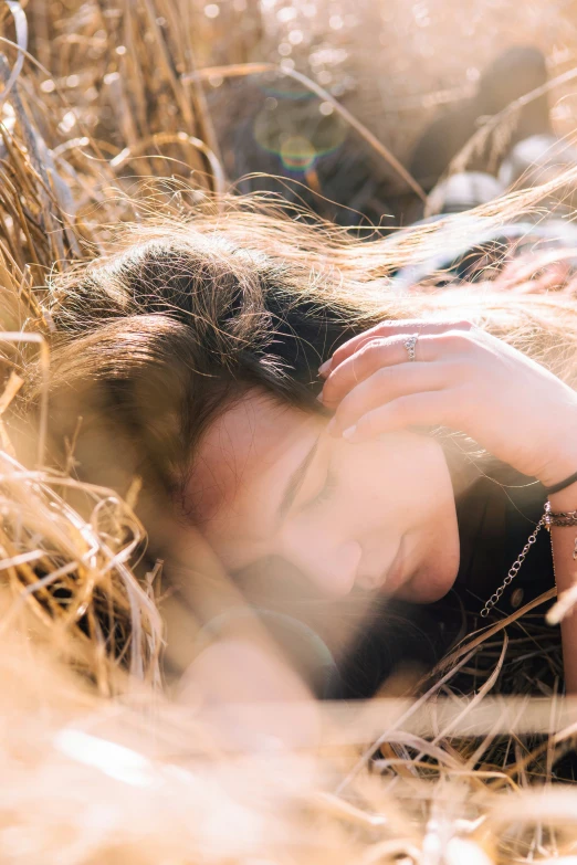 a woman is resting in some tall brown grass