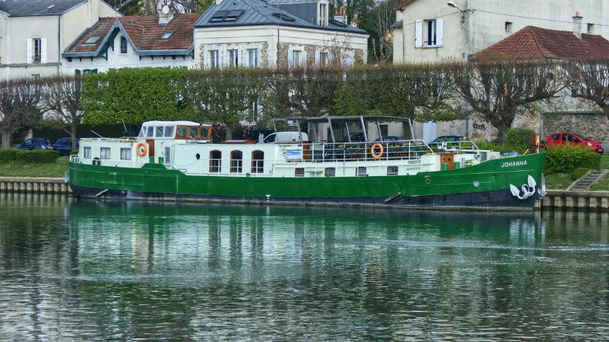 green and white boat on the water near a city