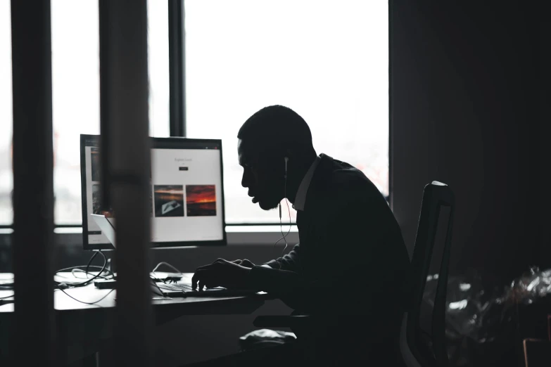 a man is sitting down working at his computer