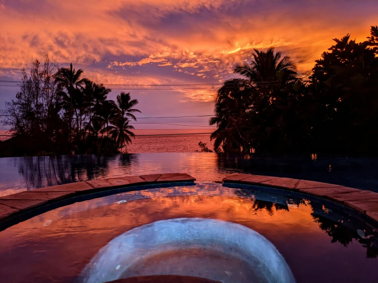 a beautiful sunset reflecting off of a swimming pool