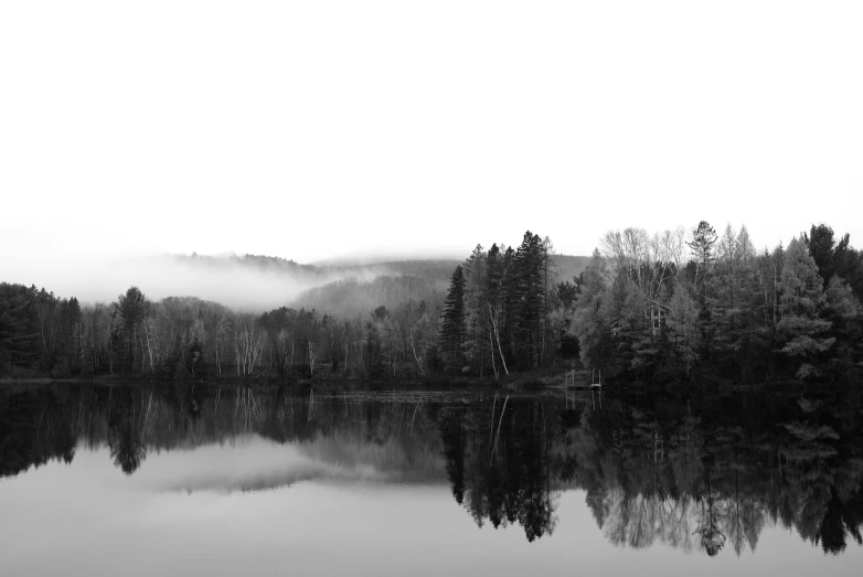 black and white po of foggy mountains over water