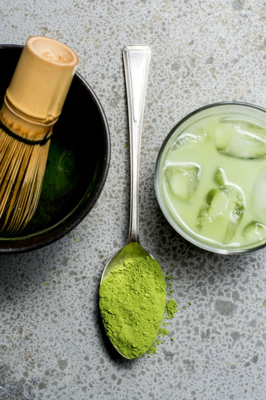 green powder with matcha in small cups, two whisk spoons