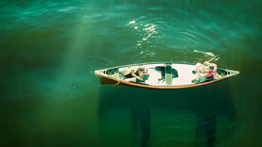 three people in a small wooden boat floating in the water