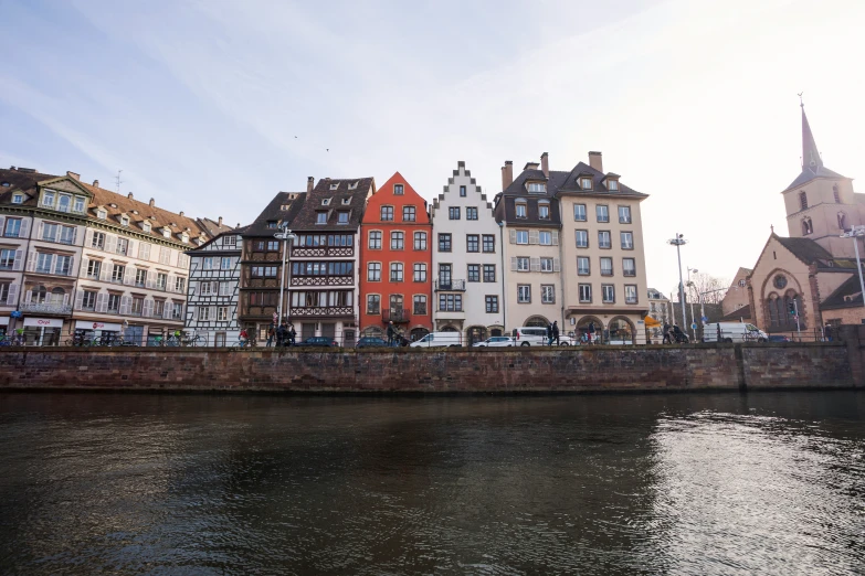 a wide river running along a city under a bright blue sky