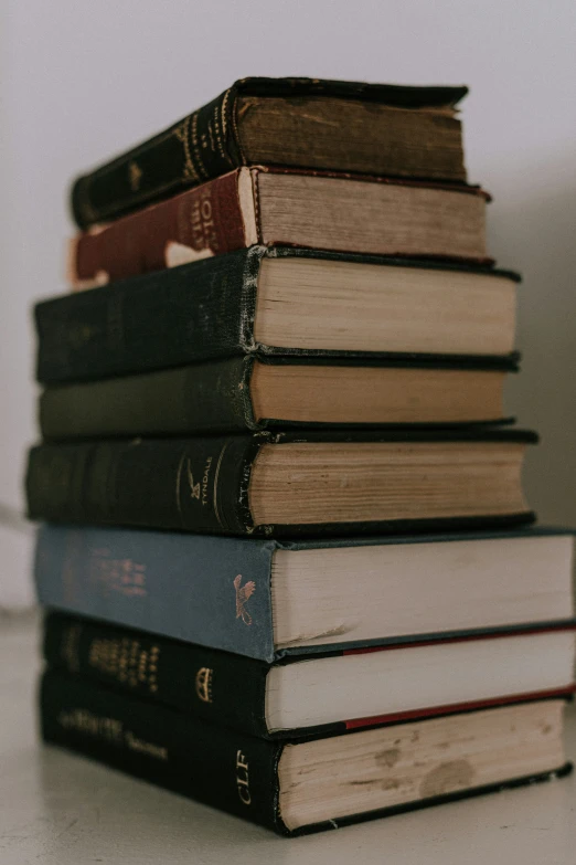 stack of books on a table top next to the corner of the wall