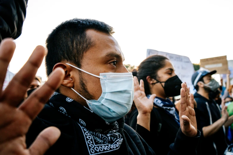 the people are holding their hands up and wearing masks