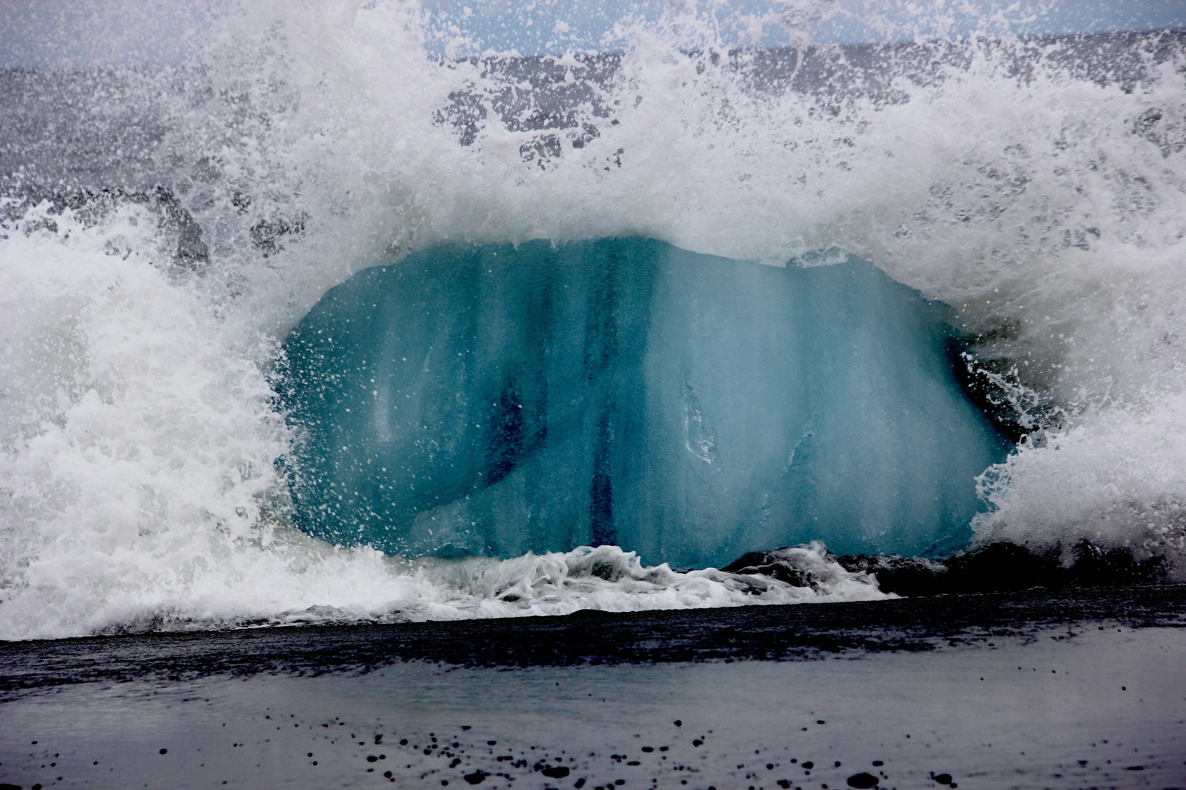 a wave crashing and breaking onto the beach shore