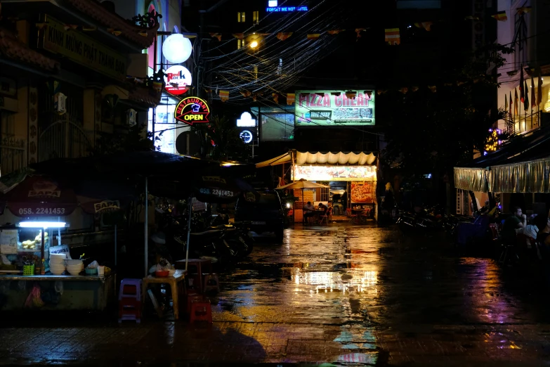 a wet city street with bright buildings at night