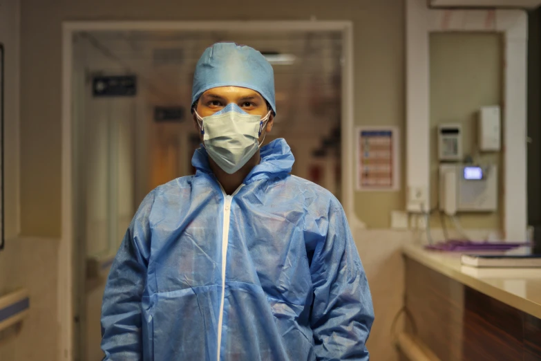 a man in a hospital gown and cap and protective mask