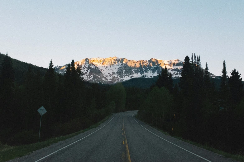 a scenic road leads to the snowy mountain range