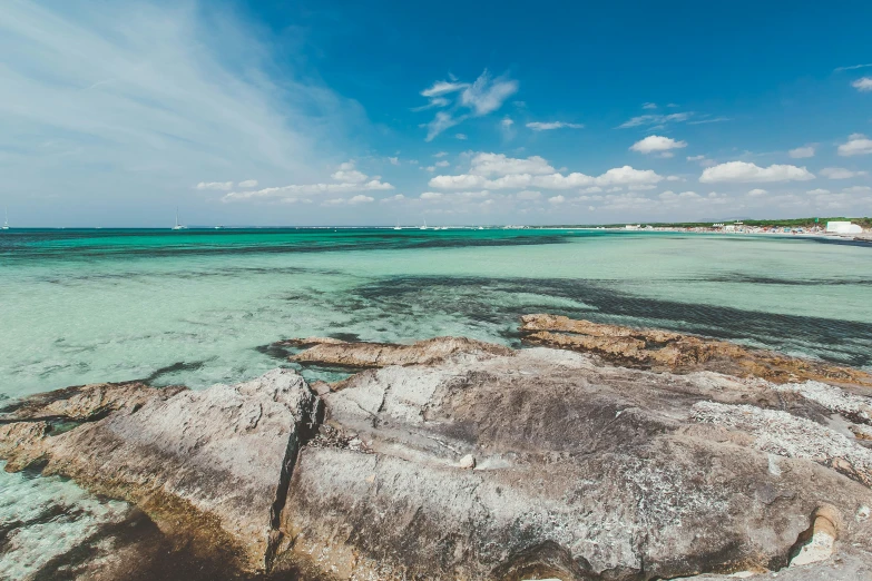 a beach with large rocks under a blue sky