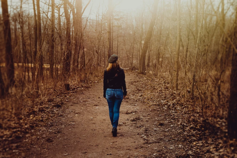 a woman walks on a path in the woods