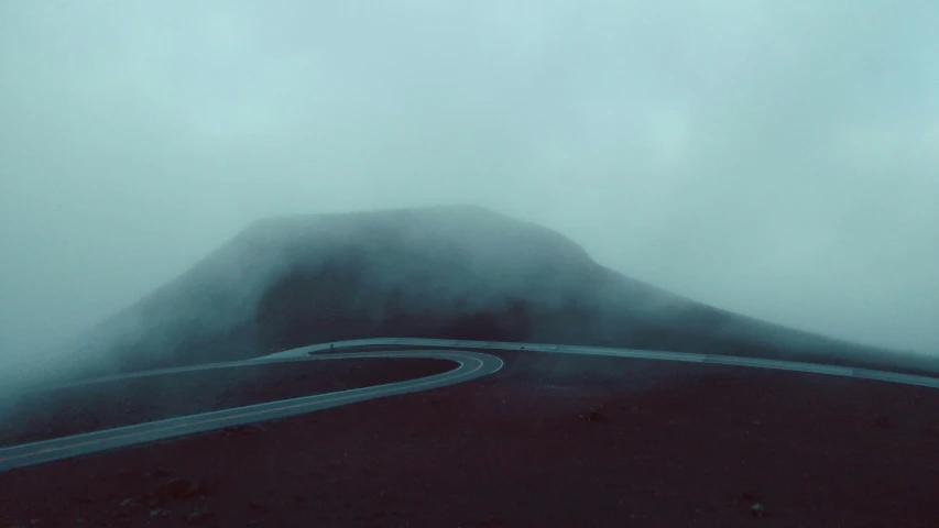 the curve of a curved road with a mountain in the background