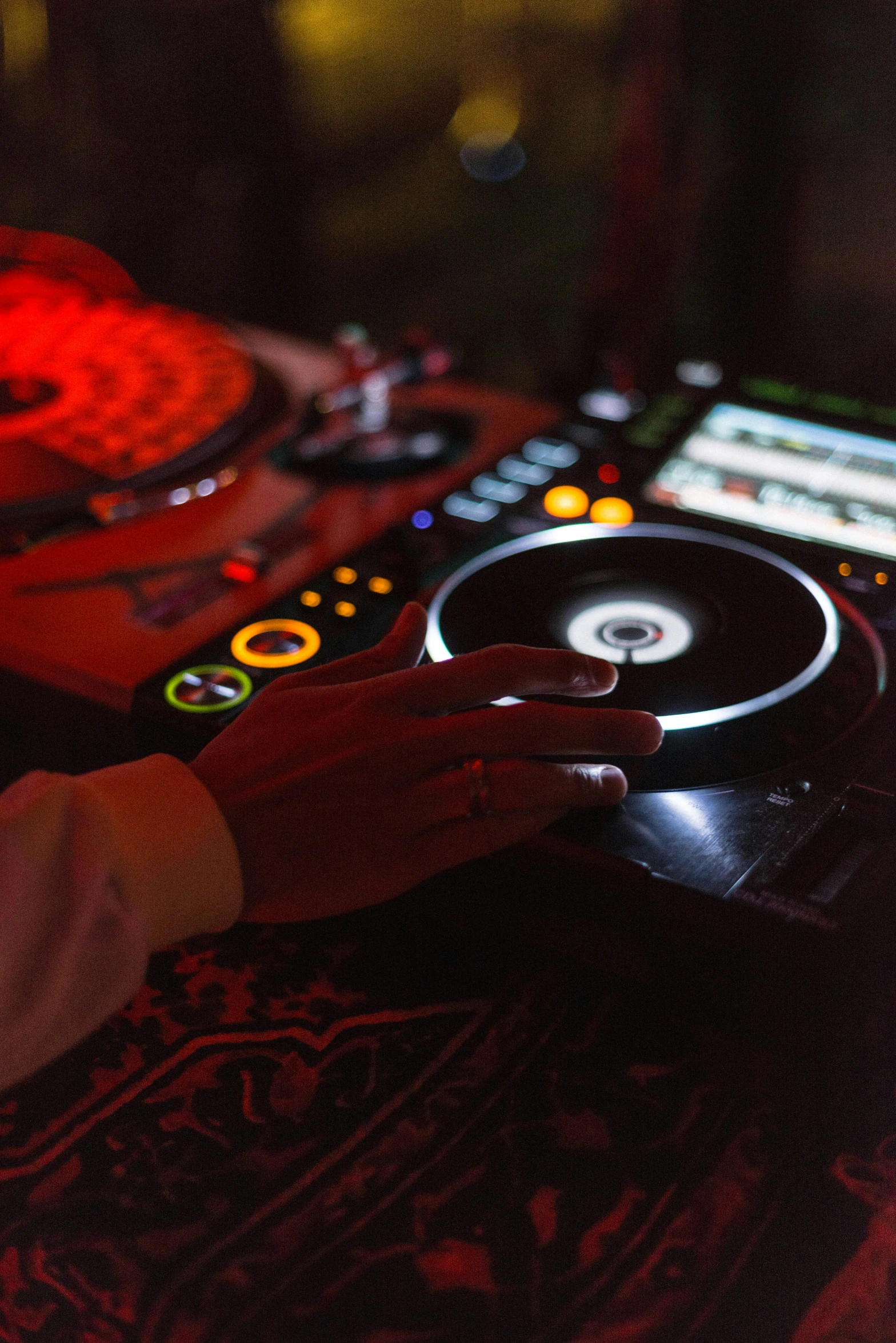 people use dj's controls on a black table in front of their recording equipment