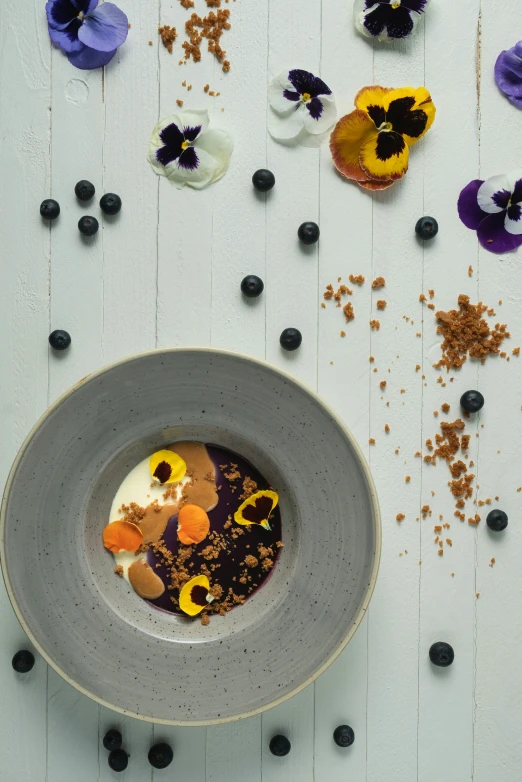 a bowl with flowers in it and some blueberries