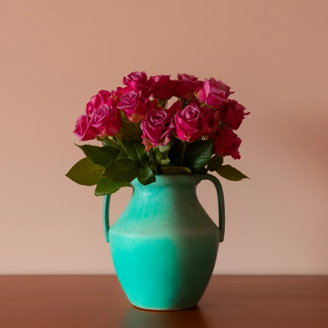 a flower arrangement in a turquoise colored vase