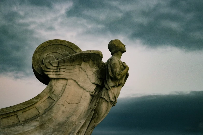 an angel statue on a cloudy day with its wings spread