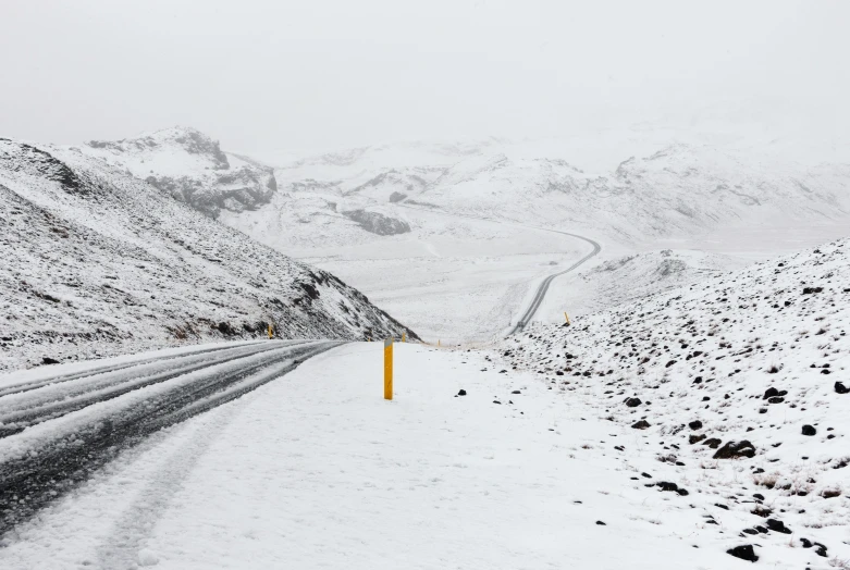 the snow covered road is lined with yellow poles