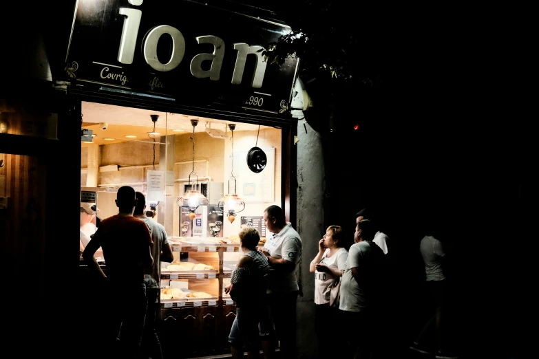 group of people standing outside an ice cream shop at night