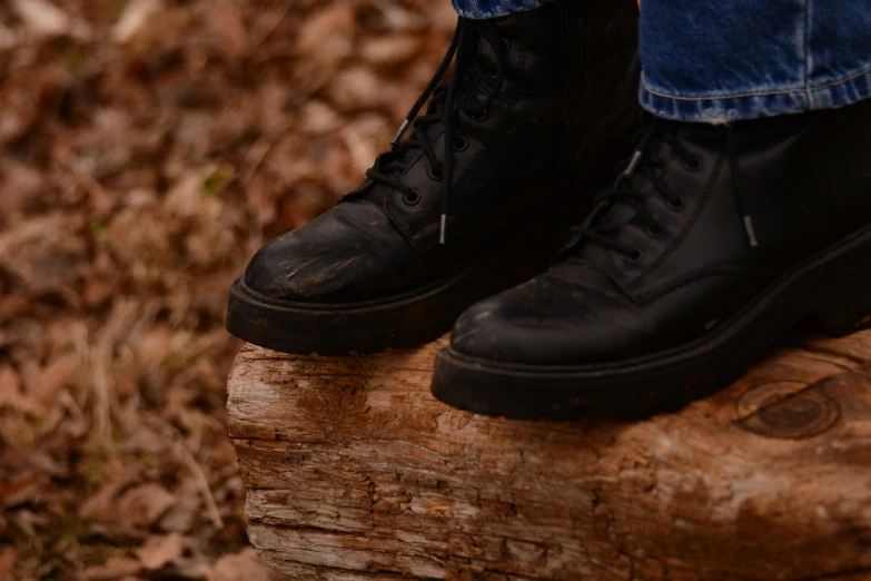 a man in black shoes standing on top of a tree stump