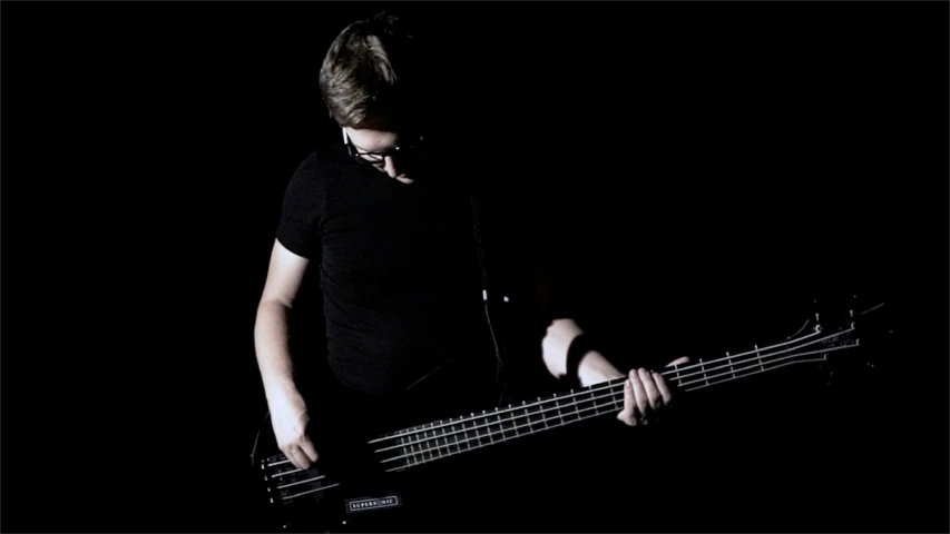 a young man playing bassoon with black background