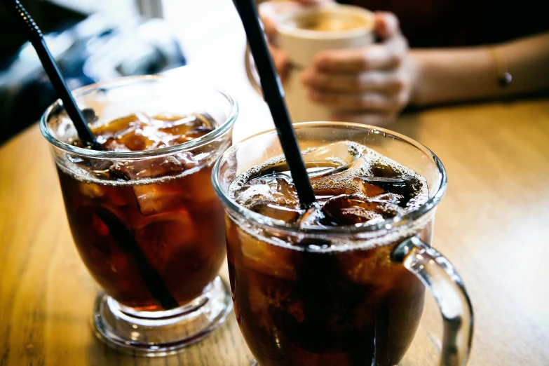 two glasses filled with iced drink sitting on a table