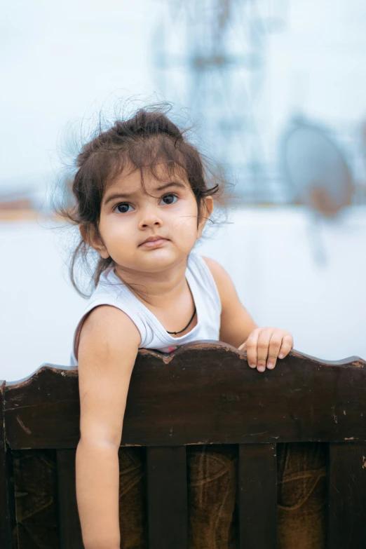 a little girl sitting on top of a bench