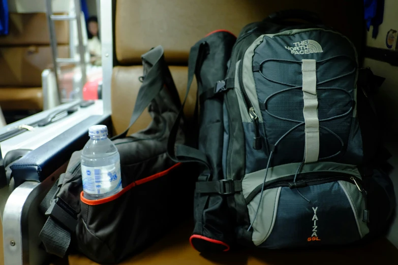 there is a back pack, water bottle and purse on the train