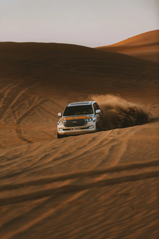 a pickup truck driving through sand dunes on a sunny day