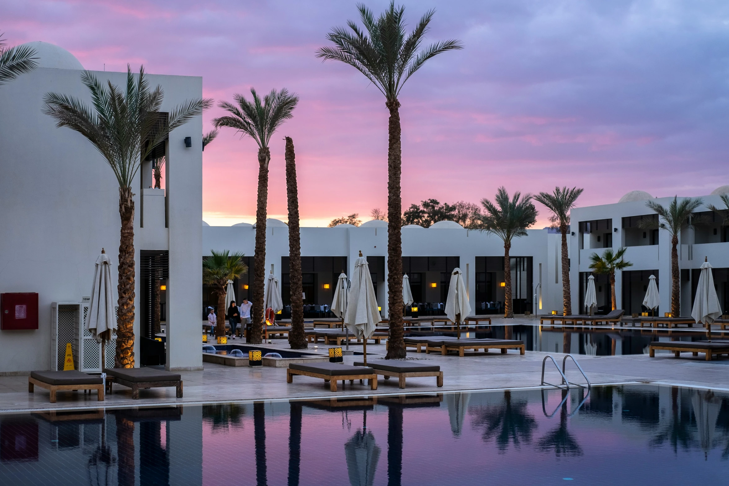 large outdoor pool at dusk with palm trees